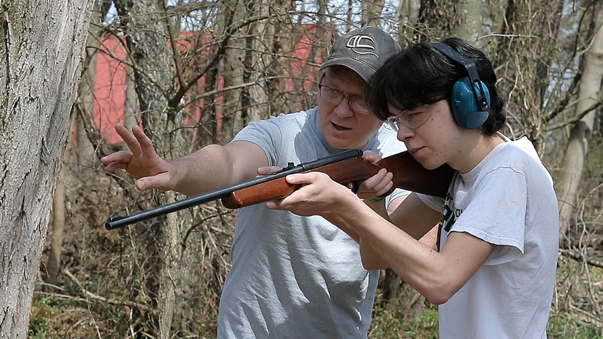 man teaching teenage boy rifle skills