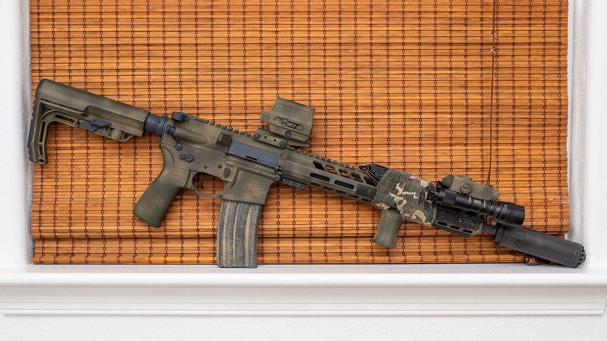 An AR-15 rifle sits on a window ledge