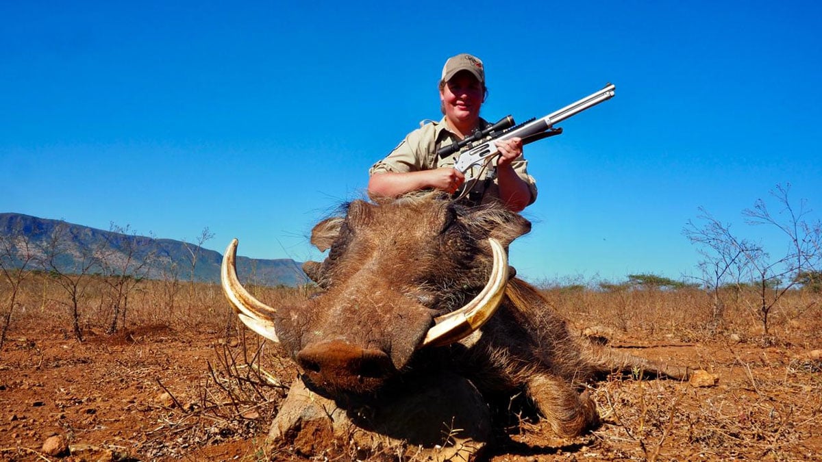 A hunter with a Henry All-Weather lever action over a downed warthog
