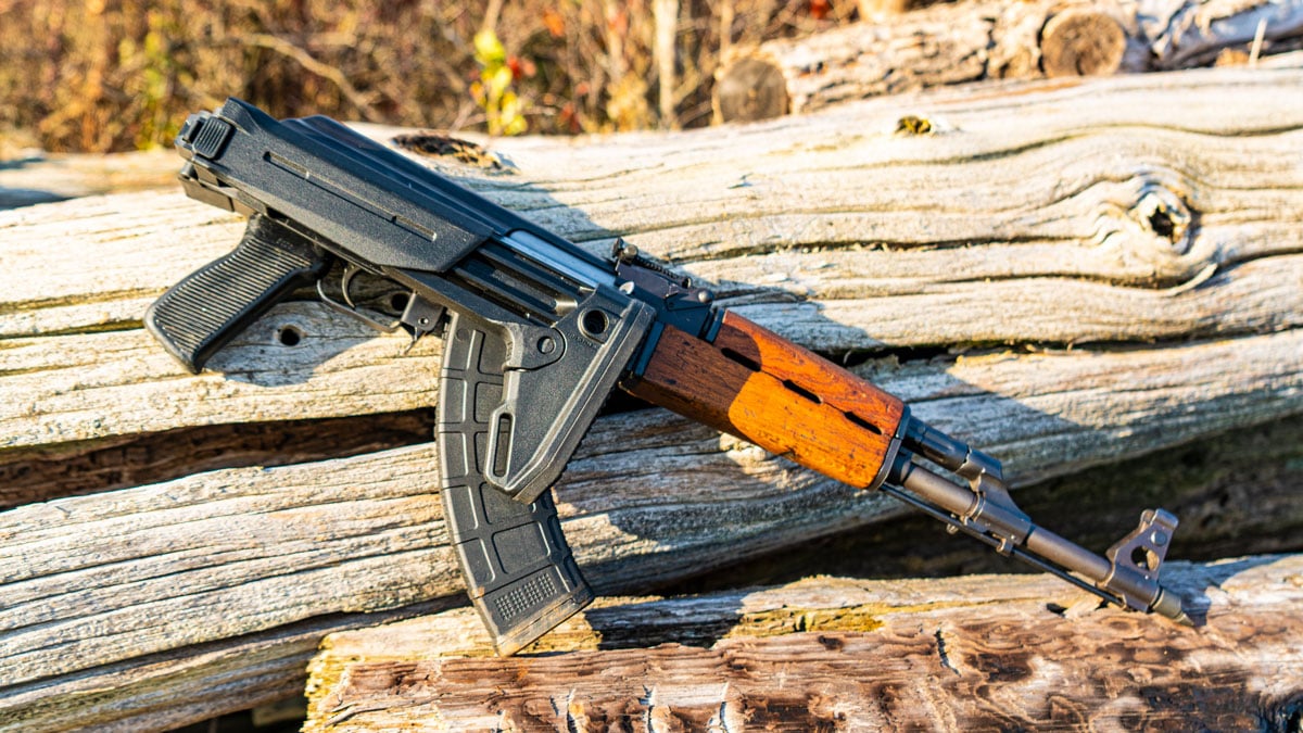 ak47 displayed on edge of fallen tree in an outdoors scene