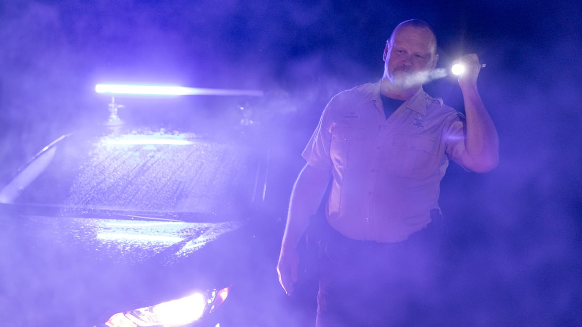 police officer with flashlight and patrol car