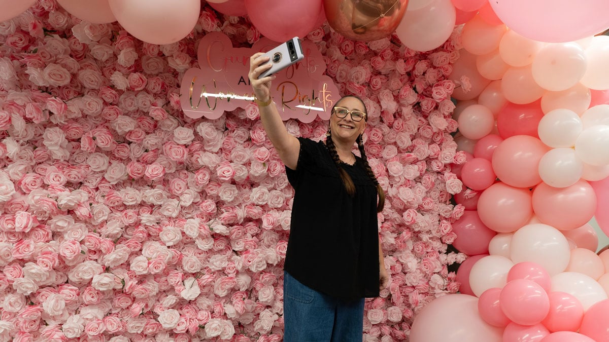 woman taking selfie in front of pink backdrop