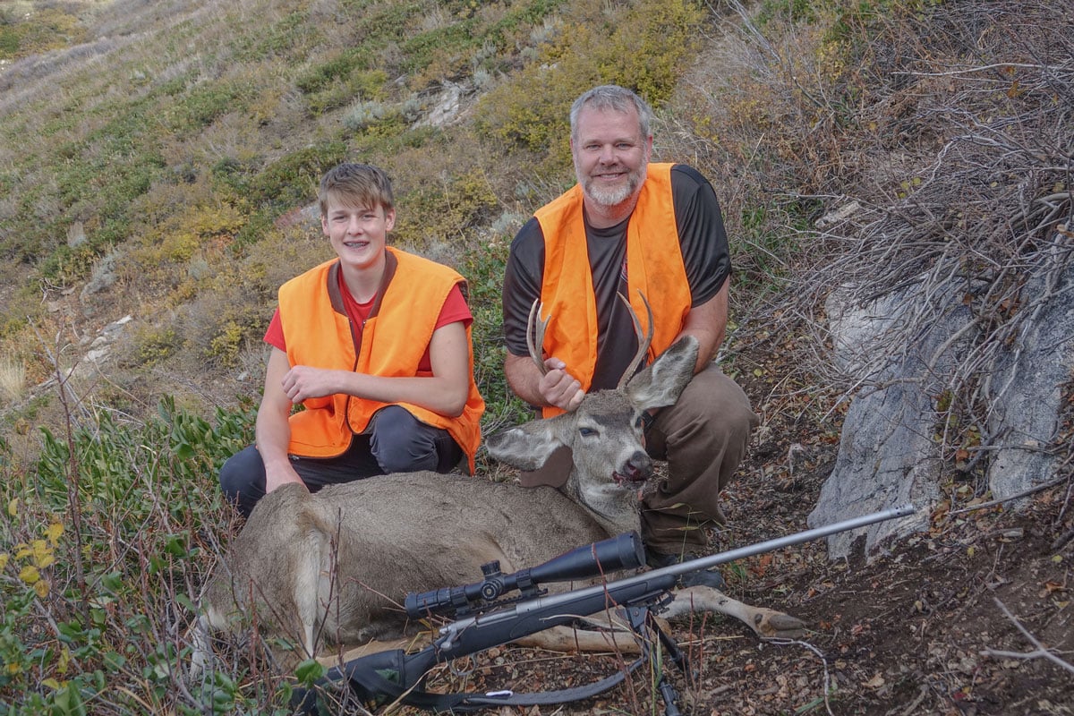 father and son hunters with deer