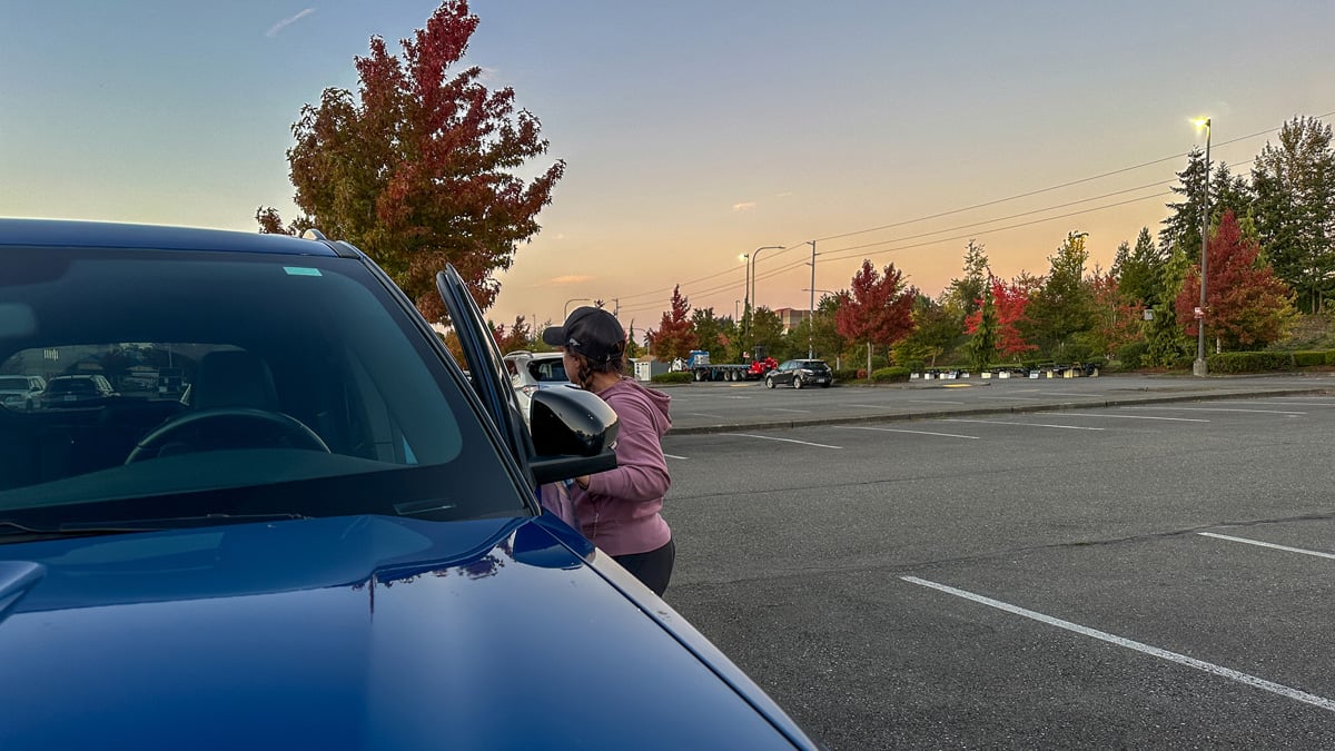 woman exiting vehicle in parking lot at dusk