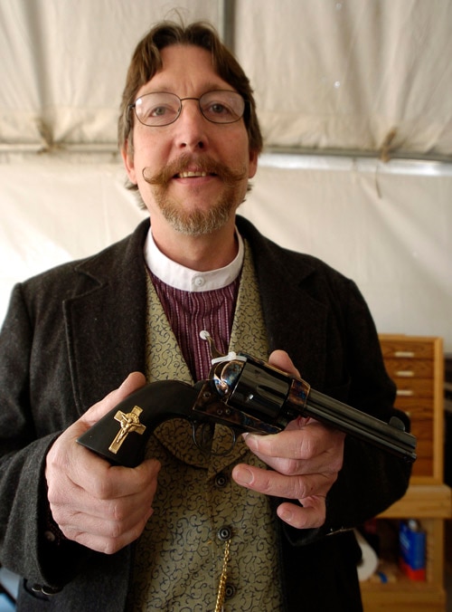 man holding handgun with cross on it