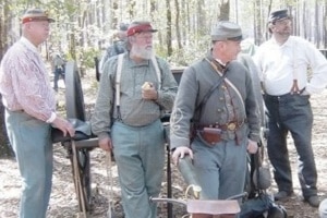 A group of Civil War reenactors standing around a cannon.