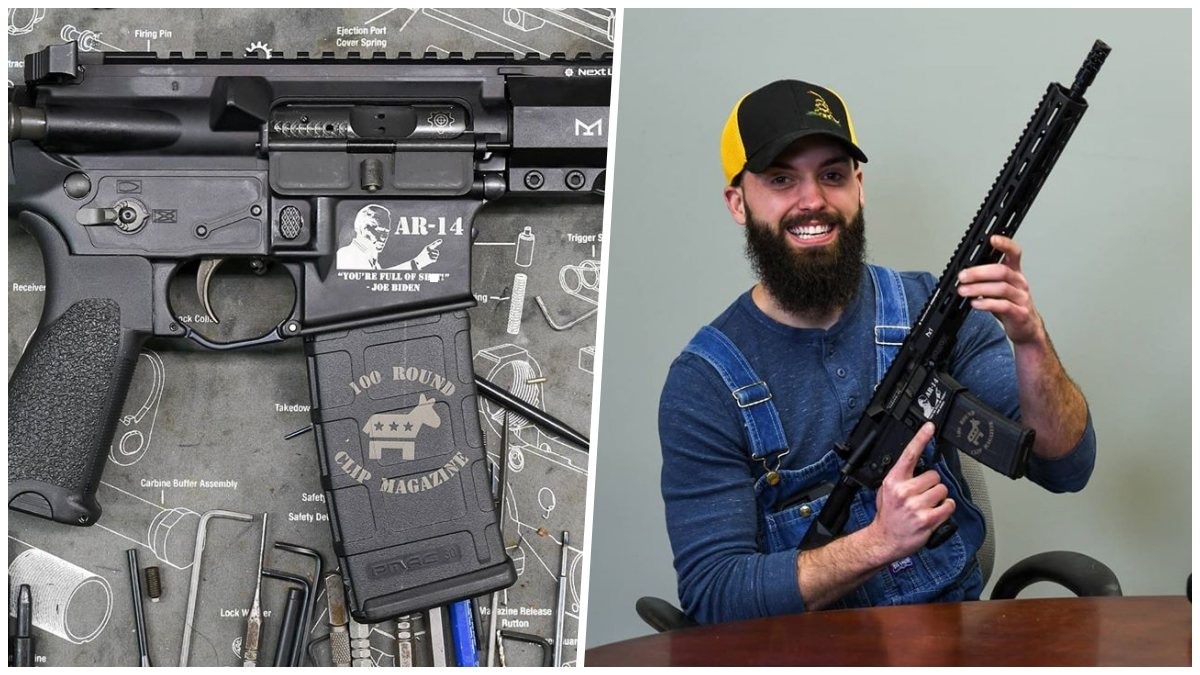 A smiling bearded man holds a new AR-14 rifle with Joe Biden's likeness on it
